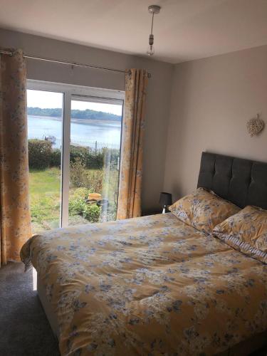 a bedroom with a bed and a large window at Oyster Bay Holiday Apartment Dundrum in Dundrum
