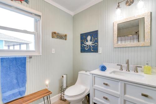 a bathroom with a toilet and a sink and a window at Lovely Crystal Beach House with Deck Walk to Ocean! in Crystal Beach