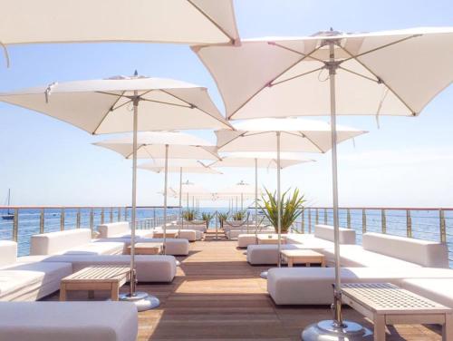 a row of white chairs and umbrellas at Portopiccolo Apartments - Loggia sul mare in Sistiana
