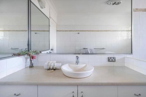 Baño blanco con lavabo y espejo en Large Private Terrace - North Facing Terrace & BBQ, en Deewhy