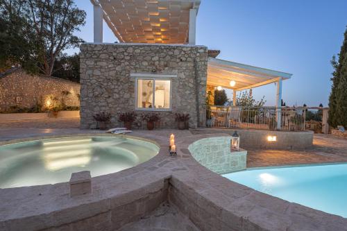 una piscina in giardino con vasca idromassaggio e una casa di Louiza - Luxury Stone Villa a Volímai