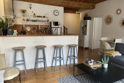a living room with a kitchen and bar with stools at Le Mercière - Joli T2 au coeur de Lyon presquîle in Lyon