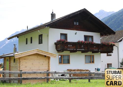 a white house with a balcony and a fence at Berghaus Martin in Neustift im Stubaital