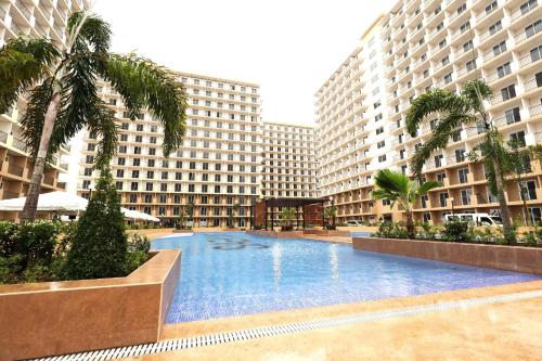 a large swimming pool with palm trees and buildings at Private studio unit with balcony near the beaches in Lapu Lapu City