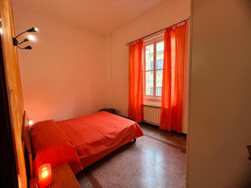 een slaapkamer met een bed en een raam met oranje gordijnen bij Appartamento Grandis in Genua