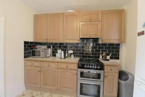 a kitchen with wooden cabinets and a stove top oven at Ross Holiday Room in Sutton