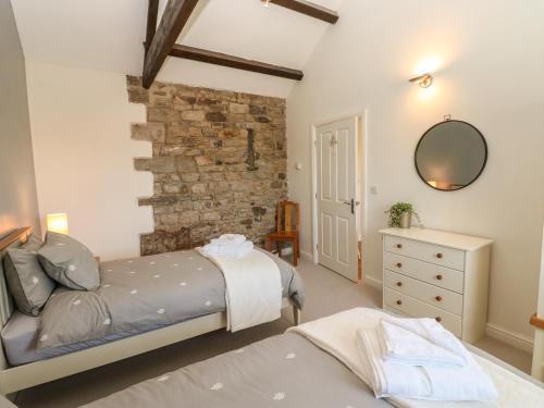 a bedroom with two beds and a stone wall at The Dairy in Bishop Auckland