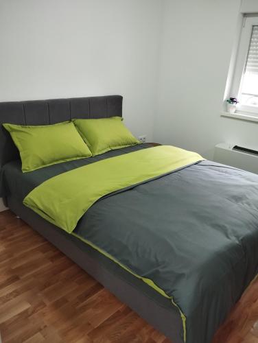 a bed with green sheets and a black headboard at Stan na dan Bijeljina Niki 2 in Bijeljina