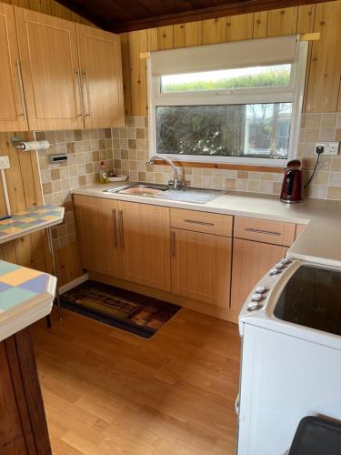 een kleine keuken met een wastafel en een raam bij Chalet 31 in Seaton