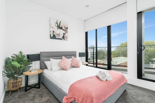 a bedroom with a bed and a large window at Sparkling New Apartment - Wollongong in Wollongong