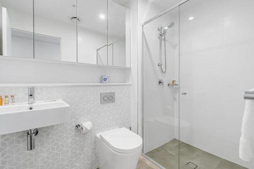 a bathroom with a shower and a toilet and a sink at Sparkling New Apartment - Wollongong in Wollongong