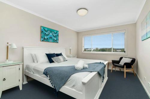 a bedroom with a white bed and a window at Spacious Townhouse in the Heart of Batemans Bay in Batemans Bay