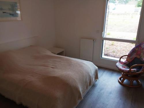 une chambre avec un lit, une chaise et une fenêtre dans l'établissement Appartement Les Flots d Arthlotte Cabellou Plage, à Concarneau