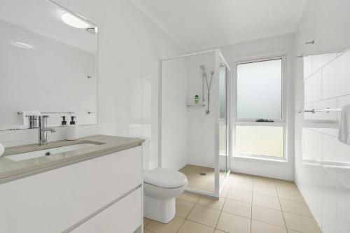 een witte badkamer met een toilet en een wastafel bij Spacious Townhouse in the Heart of Batemans Bay in Batemans Bay