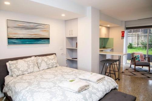 een slaapkamer met een wit bed en een keuken bij Stunning Studio by The Beach - Surf Beach in Surf Beach