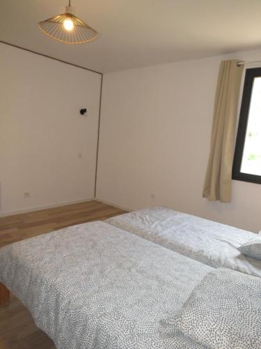 a bedroom with a white bed with a window at L'étape Dumas in Beauvène