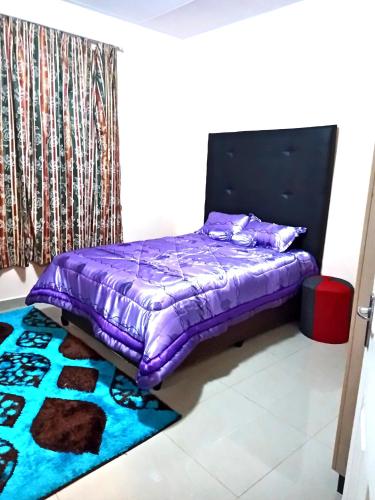 a bedroom with a purple bed and a rug at BEST APARTMENTS in Mbabane