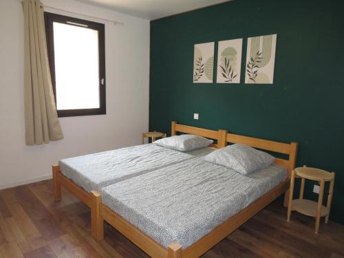 a bedroom with a bed and a green wall at L'étape Dumas in Beauvène