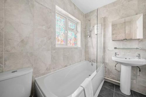 ein Badezimmer mit einer weißen Badewanne und einem Waschbecken in der Unterkunft Spacious Luxury Garden House Free Parking in Bristol