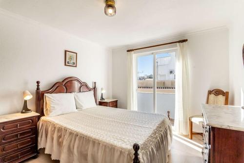 een slaapkamer met een bed en een groot raam bij Perfect house close to beach in Armação de Pêra