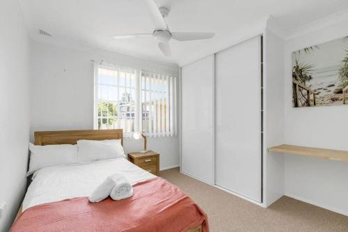 a white bedroom with a bed and a window at Lakeside Family Oasis - Oak Flats in Albion Park