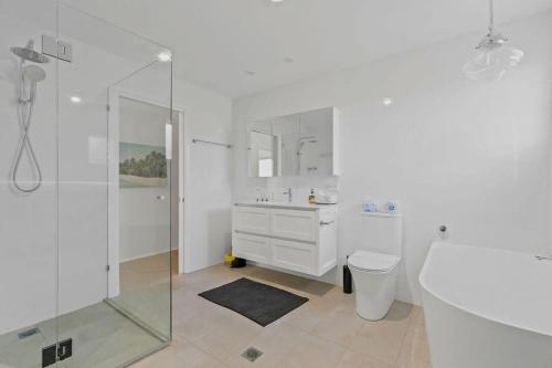 een witte badkamer met een douche en een toilet bij Lakeside Family Oasis - Oak Flats in Albion Park