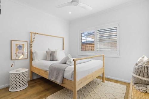 a white bedroom with a bed and a window at Coastal Retreat Long Jetty- Toowoon Bay in Long Jetty