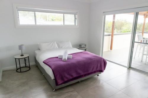 biała sypialnia z łóżkiem z fioletowym kocem w obiekcie Green Point Tranquillity w mieście Green Point