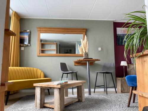 Una sala de estar con una mesa y un espejo. en PuraVida, en Westkapelle