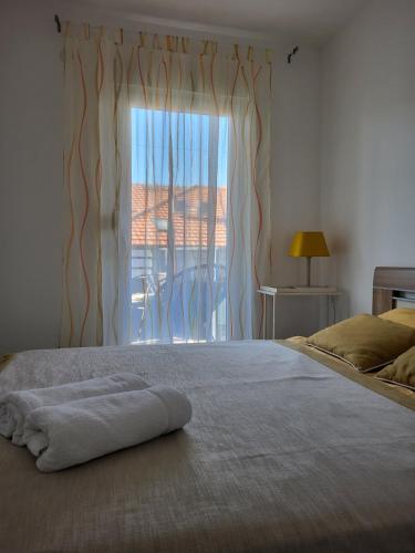 a bed with a towel on it in front of a window at Apartman J72 in Ostrovo