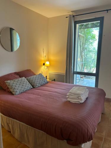 um quarto com uma cama com lençóis vermelhos e uma janela em Appartement Golf de Saumane 2 chambres 2 à 4 personnes em Saumane-de-Vaucluse