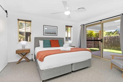 1 dormitorio con 1 cama y puerta corredera de cristal en Seaside Family Oasis - Anna Bay NSW, en Anna Bay