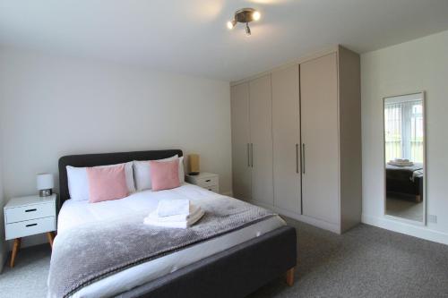 a bedroom with a large bed with pink pillows at West Finchley by Viridian Apartments in Finchley