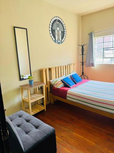 a bedroom with a bed and a chair and a mirror at Maison Verte - Budget Edition in Arequipa