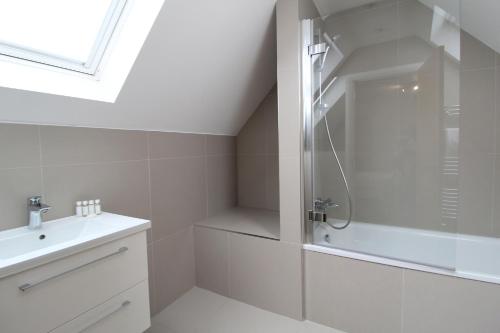 a white bathroom with a shower and a sink at West Finchley by Viridian Apartments in Finchley
