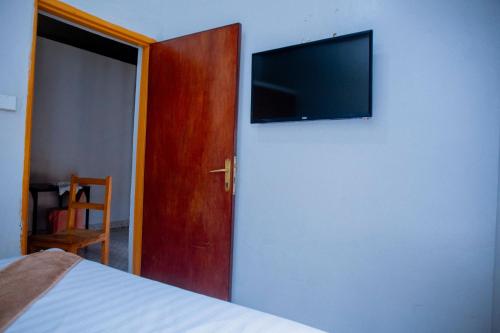 een slaapkamer met een bed en een flatscreen-tv aan de muur bij SKYLIGHT MOTEL Airport Road in Kigali
