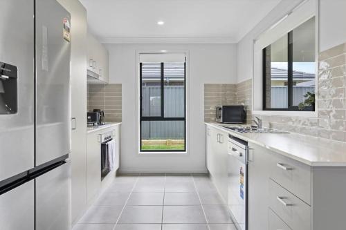a kitchen with white cabinets and a window at Time Out - Beautifully decorated new home in Cessnock