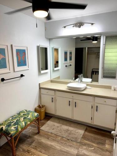 uma casa de banho com um lavatório, um espelho e uma cadeira em IslandVista 1BR: Ocean & Golf Bliss em Kahana