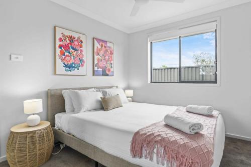 a white bedroom with a large bed and a window at Time Out - Beautifully decorated new home in Cessnock