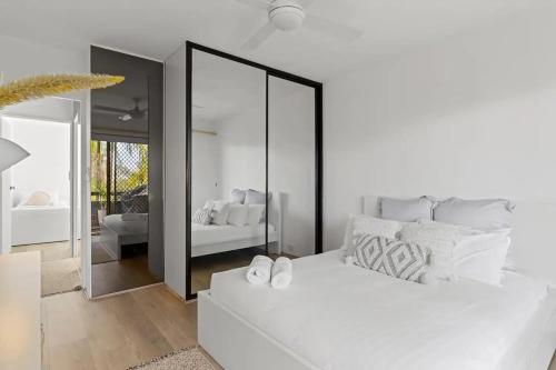 a bedroom with a white bed and a mirror at Beachside Serenity - 100m to Beach in Nelson Bay