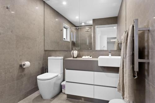 a bathroom with a toilet and a sink and a mirror at Catch the Breeze - Pet Friendly Townhouse in Newcastle
