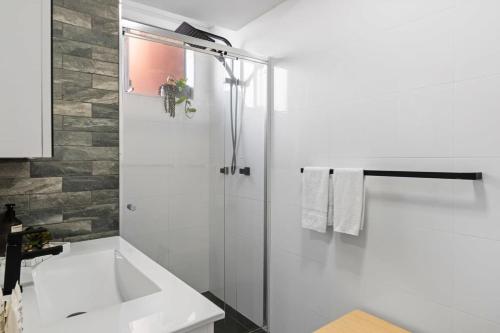 a white bathroom with a shower and a sink at Seascape - 500m to Merewether Ocean baths in Merewether