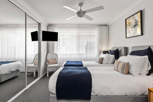 a bedroom with two beds and a ceiling fan at Hitters Paradise - Stay & Play in Salamander Bay in Salamander Bay