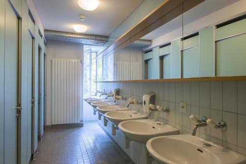 uma casa de banho com uma fila de lavatórios e espelhos em Schaffhausen Youth Hostel em Schaffhausen