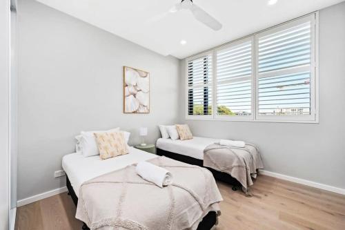 a white room with two beds and a window at Harbour-View Luxury - Herald Building Newcastle in Newcastle