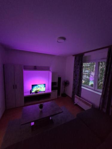 d'un salon avec une télévision et un éclairage violet. dans l'établissement Apartman, à Brčko