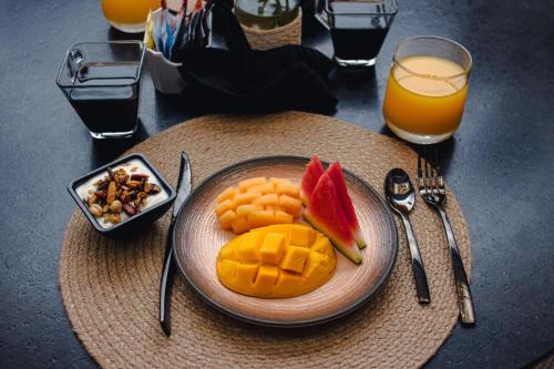 a plate of fruit on a table with a glass of orange juice at Casa Continental Hotel Boutique & Suites - Adults Only in Mérida