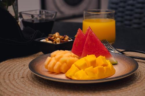 a plate of fruit on a table with a glass of orange juice at Casa Continental Hotel Boutique & Suites - Adults Only in Mérida