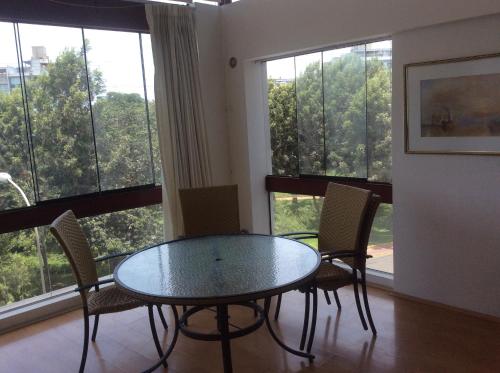 ein Esszimmer mit einem Tisch, Stühlen und Fenstern in der Unterkunft Departamento Dúplex in Lima