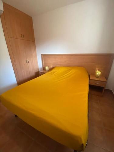 - un lit jaune dans une chambre avec 2 tables de chevet dans l'établissement Appartement en bord de mer avec piscine, à San-Nicolao